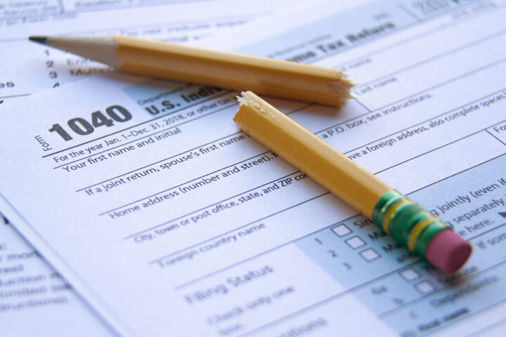 Concept image for tax anger or frustration of a broken pencil lying on IRS form 1040 paperwork