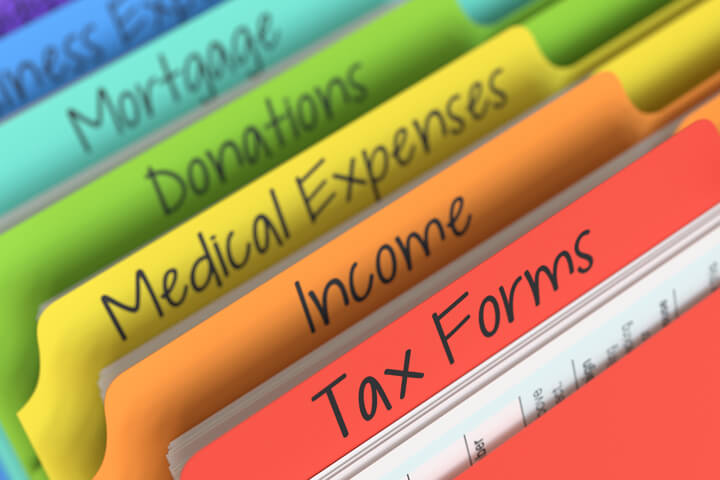 Rainbow-colored tax folders at angle in filing cabinet with camera depth of field blur