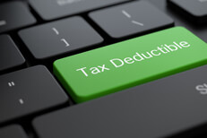 Tax deductible keyboard key Dark laptop keyboard with bright green tax deductible key concept for online deduction research