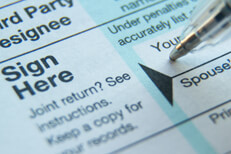 Close view of ballpoint pen signing signature line on 1040 tax form