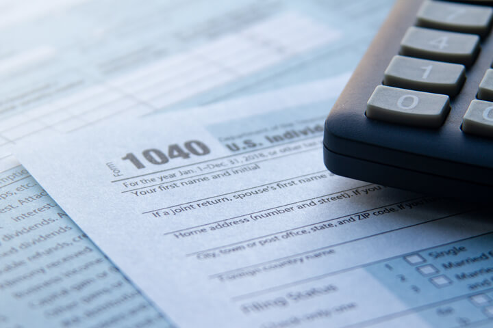 IRS form 1040 paperwork with corner of calculator and depth of field blur