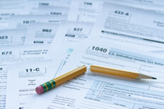 Tax forms with broken pencil Many IRS tax forms laid out on desk with broken pencil concept for tax reform or simplification