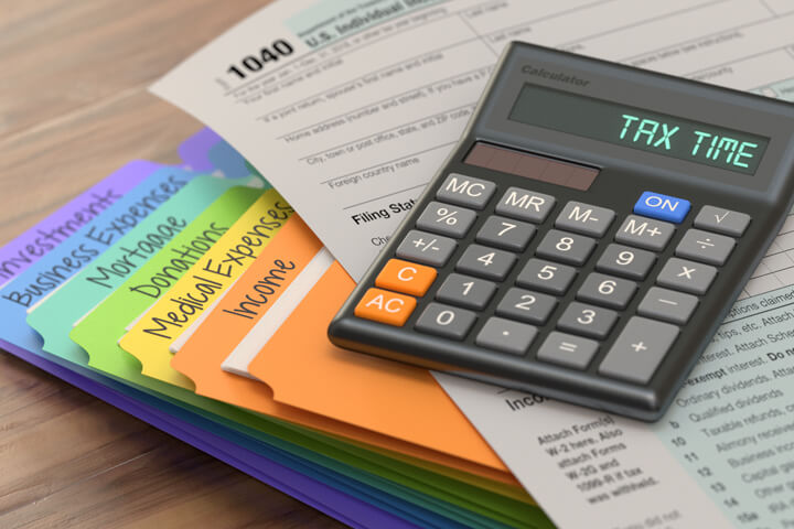 Rainbow manila tax folders with 1040 IRS form and calculator with LCD reading Tax Time