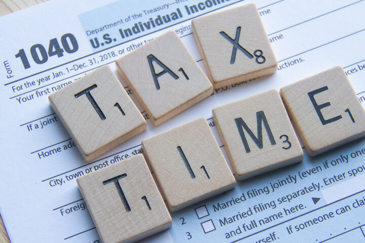 IRS form 1040 with Scrabble letters reading TAX TIME lying on top