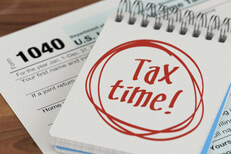 Tax time spiral notebook Spiral notebook with Tax Time written in red marker lying on IRS form 1040 on desk