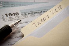 2018 taxes IRS 1040 Manila folder with 2018 taxes tab on IRS form 1040 with ballpoint pen