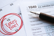Tax form on tax calendar Calendar page with 15 circled and taxes due in red marker with 1040 form on top