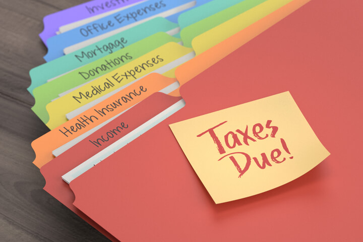 Colorful manila tax category folders with Taxes Due sticky note