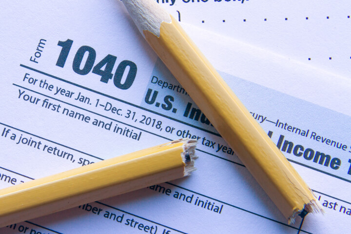 Photo from top view of broken pencil on IRS form 1040 concept for tax frustration