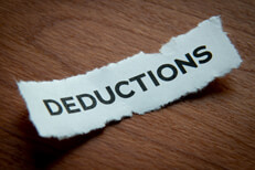 Torn paper tax deductions Torn piece of paper with Deductions text vignetted on woodgrain background