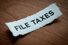 Torn paper file taxes text Torn piece of paper with the text File Taxes printed on it with vignette on wood background
