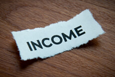 Torn paper income text Torn piece of paper with word Income on depth of field and vignette on wood surface