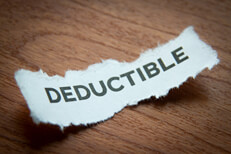 Tax deductible torn paper piece Piece of torn paper printed with Tax Deductible text concept image with vignette and woodgrain