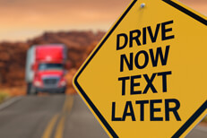 Drive now text later sign Road sign reading drive now text later with large semi burred in distance