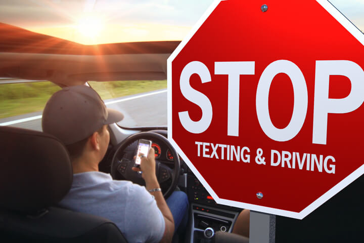 Man driving into sunset texting on cell phone with stop texting and driving stop sign