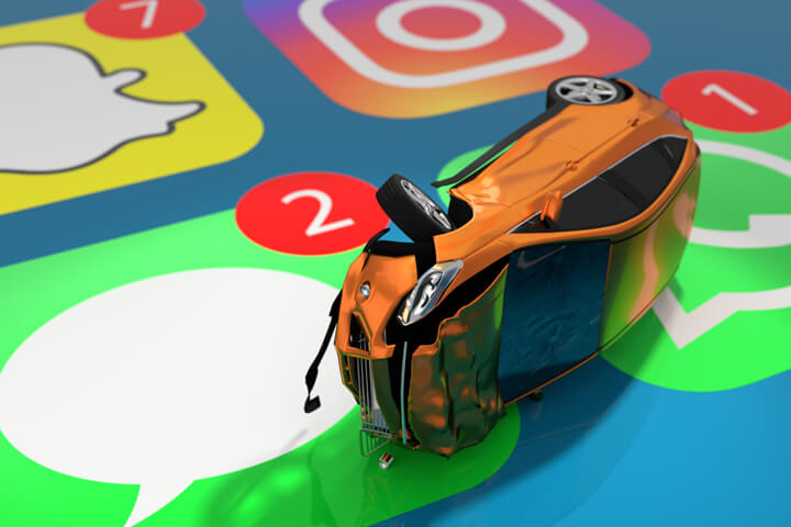 Small orange car with accident damage lying on close up cell phone screen showing Snap Chat, Instagram, iMessage, and Whats App icons