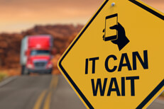 Texting can wait sign Road sign reading It Can Wait with texting icon and oncoming semi truck blurred in background
